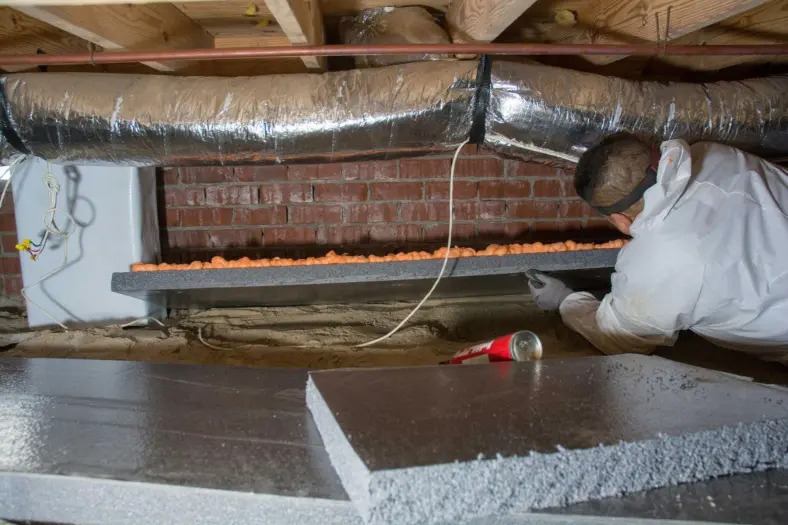 Crawl space insulation installation in Olympia, WA — rigid foam board fitted against the foundation wall